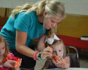 One of the teenagers from Kingsville Baptist helps one of the children with a craft during Vacation Bible School at Forest Hill Baptist Church. Photo taken by Joe Dupree