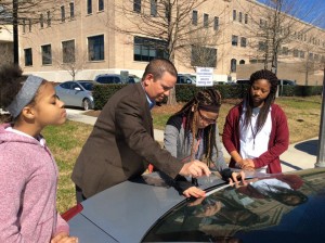 Covington Police Chief Tim Lentz helps some teenagers place "In God We Trust" decals on one of the city's police vehicles. Photo courtesy of Covington Police Department