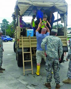 National Guardsmen load the Phillips family from the Bridge Church in Madisonville on a truck to evacuate. Lane Corley photo