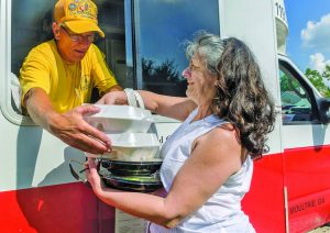 Southern Baptist Disaster Relief team member Jerry Ritter, a member of Blackgum First Baptist Church in Vian, Okla., hands two hot meals to flood survivor Pat Thomas, a member of Healing Place Church of Baton Rouge.  Carmen K. Sisson photo
