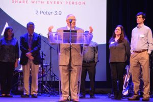 Wayne Sheppard, executive assistant to the LBC executive director, stands individuals who play key roles in some of the missions partnerships that Louisiana Baptists play a role with around the world.