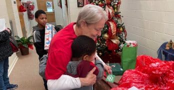 Thieda Edwards embracing a child during the Christmas gift giveaway at Homewood Baptist Church, Alexandria. Brian Blackwell photo